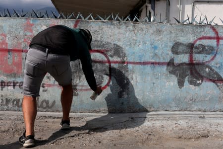 Artist Fabian Solymar paints a graffiti over a wall with a paint depicting the eyes of late President Hugo Chavez at the Petare slum, in Caracas