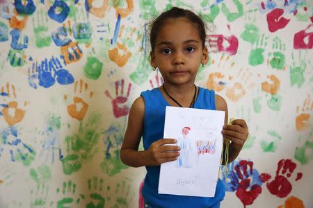 Iyari Suarez, 3, holds a drawing she drew which depicts the late Venezuelan President Hugo Chavez, during a writing workshop at 4F military fort in Caracas December 14, 2014. REUTERS/Carlos Garcia Rawlins