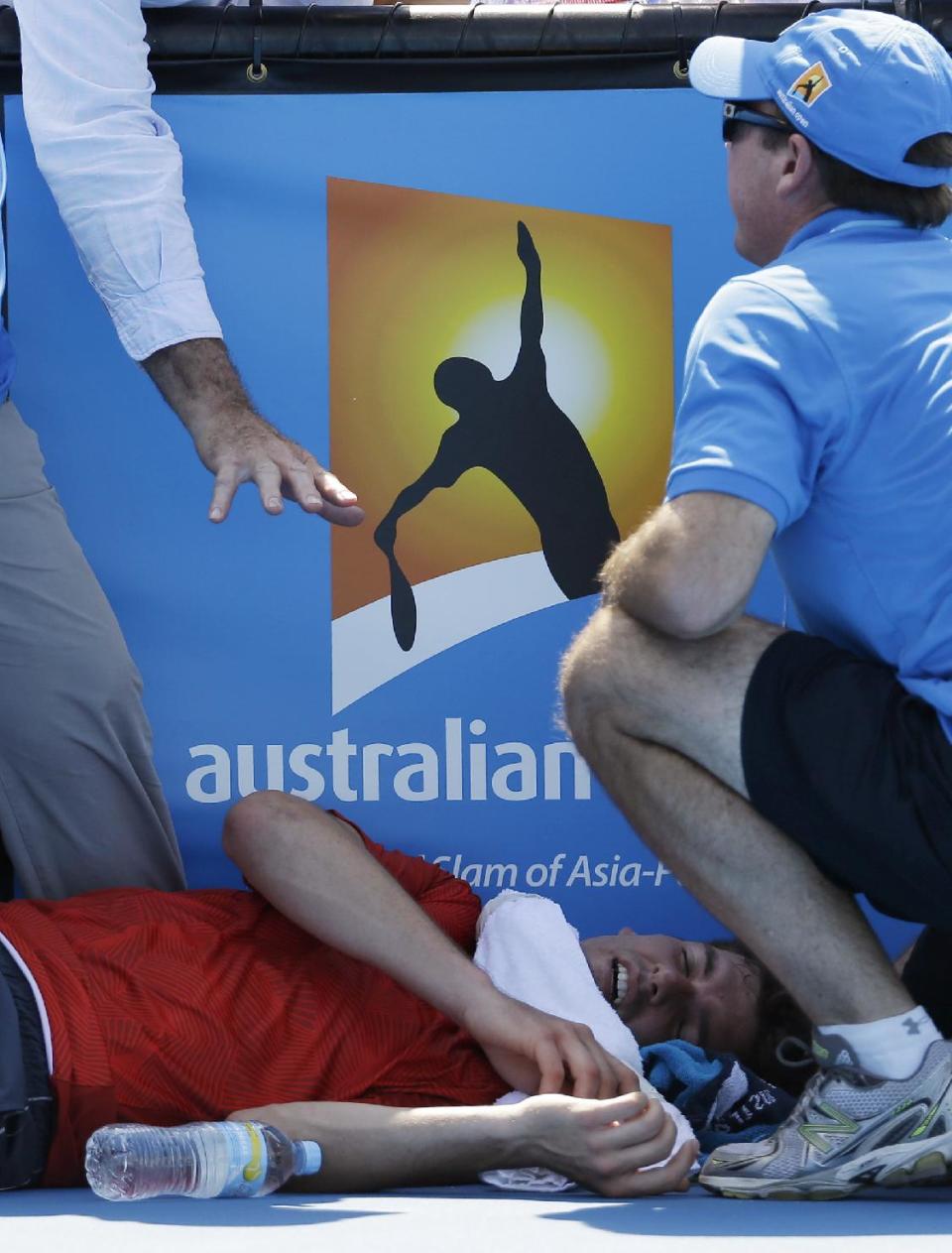 Frank Dancevic of Canada lies on the court after collapsing during his first round match against Benoit Paire of France as temperatures topped at 43 C (108 F) at the Australian Open tennis championship in Melbourne, Australia, Tuesday, Jan. 14, 2014. (AP Photo/Aijaz Rahi)