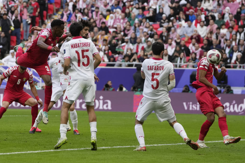 Jordan's Abdallah Nasib, left top, heads the ball as Tajikistan's Vahdat Hanonov, top right covered, scores an own goal during the Asian Cup quarterfinal soccer match between Tajikistan and Jordan, at Ahmad Bin Ali Stadium in Al Rayyan, Qatar, Friday, Feb. 2, 2024. (AP Photo/Thanassis Stavrakis)