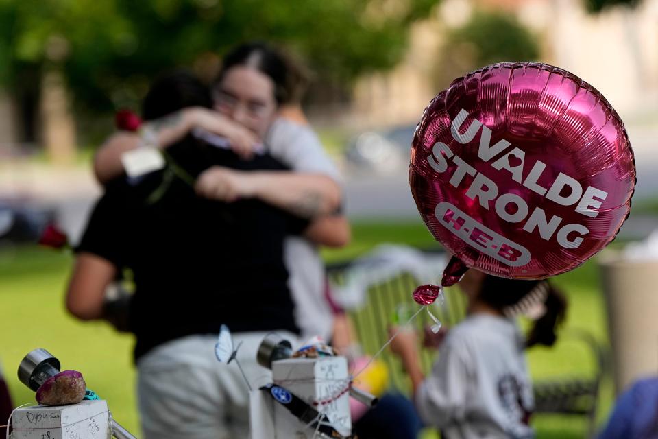 May 24, 2023: Visitors hug as they place flowers at a memorial in Uvalde, Texas. One year ago a gunman killed 19 children and two teachers inside a fourth-grade classroom at  Robb Elementary School in Uvalde.