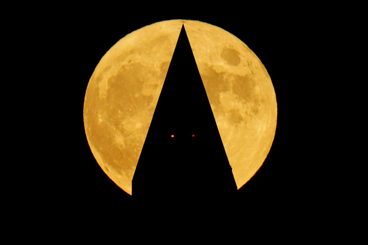 A full Hunter's moon rises behind the Washington Monument, in Washington, Sunday, Oct. 9, 2022.