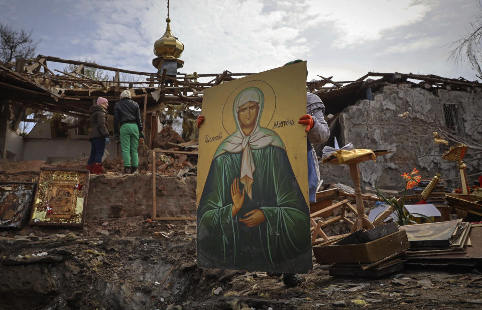 CAPTION CORRECTS TOWN SPELLING - People save icons as they clear the rubble after a Russian rocket ruined an Orthodox church in rocket attack on Easter night, a crater left by the rocket in the foreground, in Komyshuvakha, Zaporizhzhia region, Ukraine, early hours Sunday, April 16, 2023. (AP Photo/Kateryna Klochko)