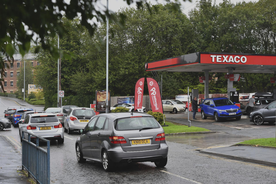 Cars queue at a petrol station in Stalybridge, England, Saturday Sept. 25, 2021. The haulage industry says the U.K. is short tens of thousands of truckers, due to a perfect storm of factors including the coronavirus pandemic, an aging workforce and an exodus of European Union workers following Britain’s departure from the bloc. BP and Esso shut a handful of their gas stations this week, and motorists have formed long lines as they try to fill up in case of further disruption. (Anthony Devlin/PA via AP)