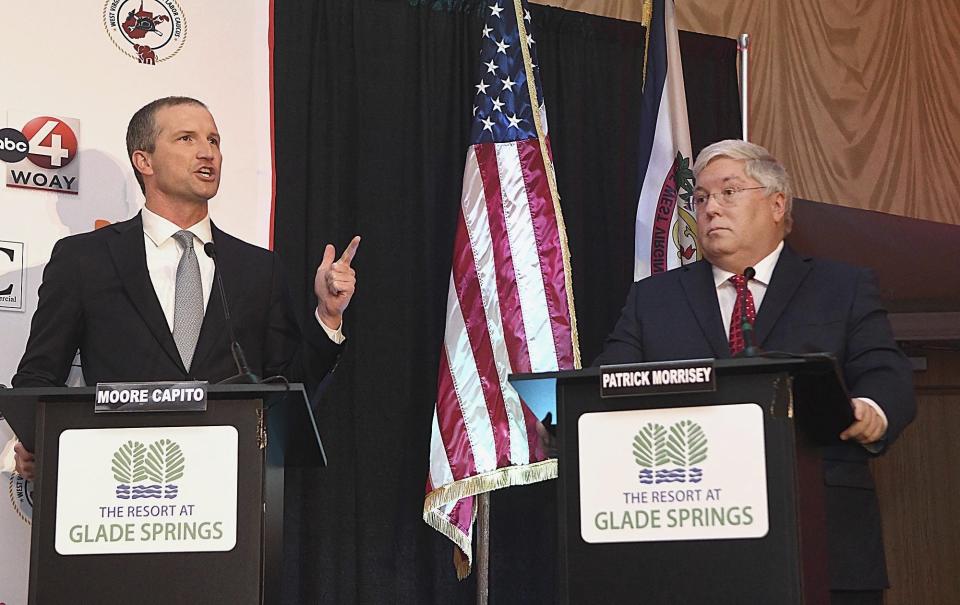 Gubernatorial candidate Moore Capito, left, speaks as Attorney General and candidate Patrick Morrisey listens during a GOP debate held at The Resort at Glade Springs on Tuesday, Feb. 6, 2024, in Daniels, W.V. (Rick Barbero/The Register-Herald via AP)