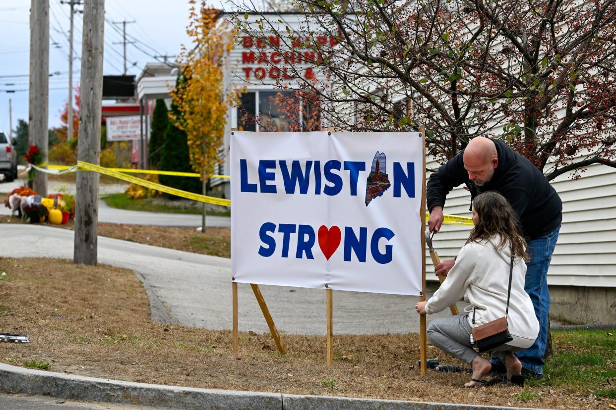 A Lewiston couple places a "Lewiston Strong" banner outside the Schemengees Bar & Grille Restaurant.