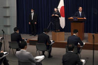 Japan's Prime Minister Yoshihide Suga, right, speaks during a press conference at the prime minister's official residence Friday, May 28, 2021, in Tokyo. Japan extended a coronavirus state of emergency in Tokyo and other areas for 20 more days on Friday, with infections still not slowing as it prepares to host the Olympics in just over 50 days. (Behrouz Mehri/Pool Photo via AP)