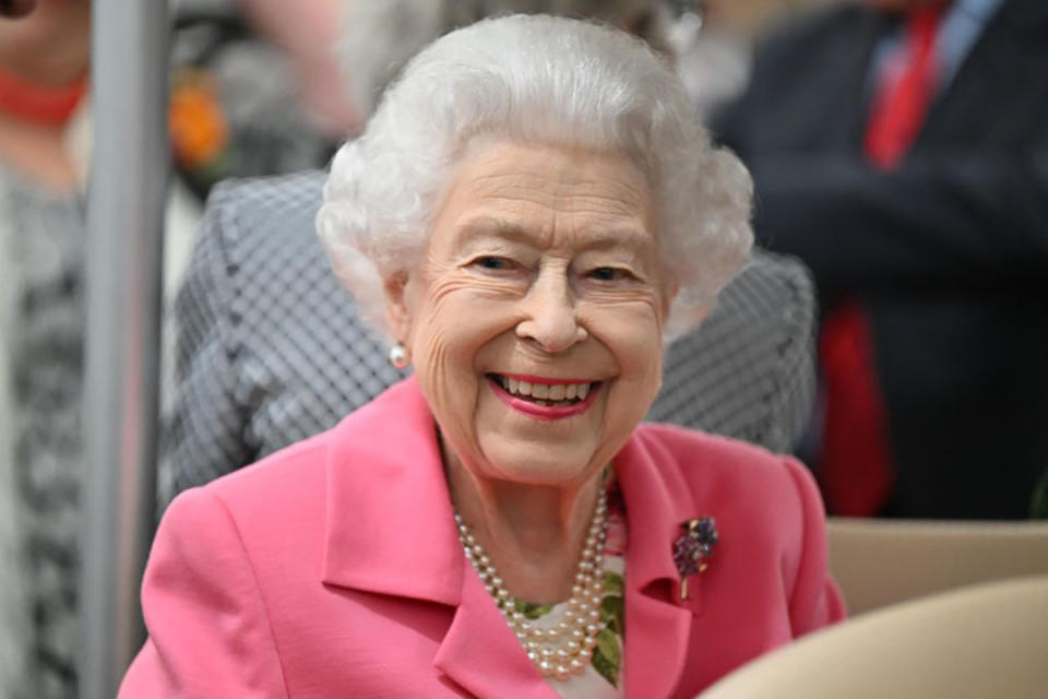 The Queen smiles in a bright pink coat.