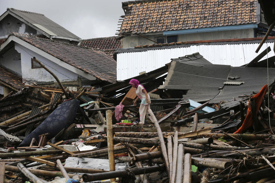 A woman walks on the debris following the tsunami in Sumur, Indonesia, Tuesday, Dec. 25, 2018. The Christmas holiday was somber with prayers for tsunami victims in the Indonesian region hit by waves that struck without warning Saturday night.(AP Photo/Tatan Syuflana)