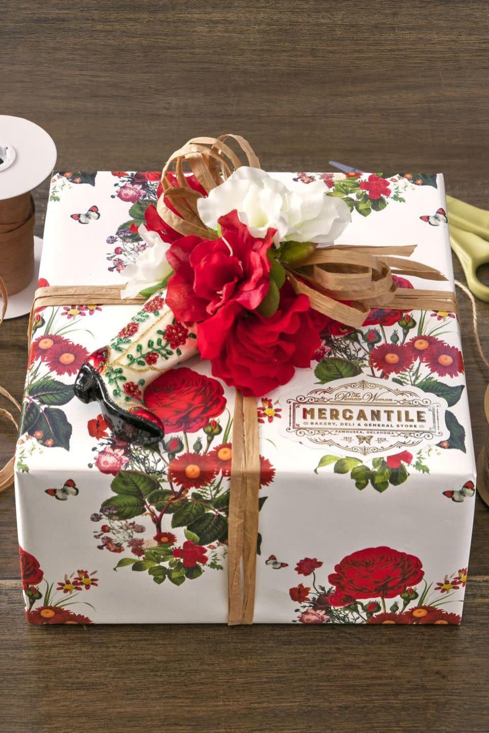 <p>Affix faux flowers in Christmas colors and a matching ornament to your beautifully wrapped gift. You can mimic this exact design that The Mercantile created for guests.</p>