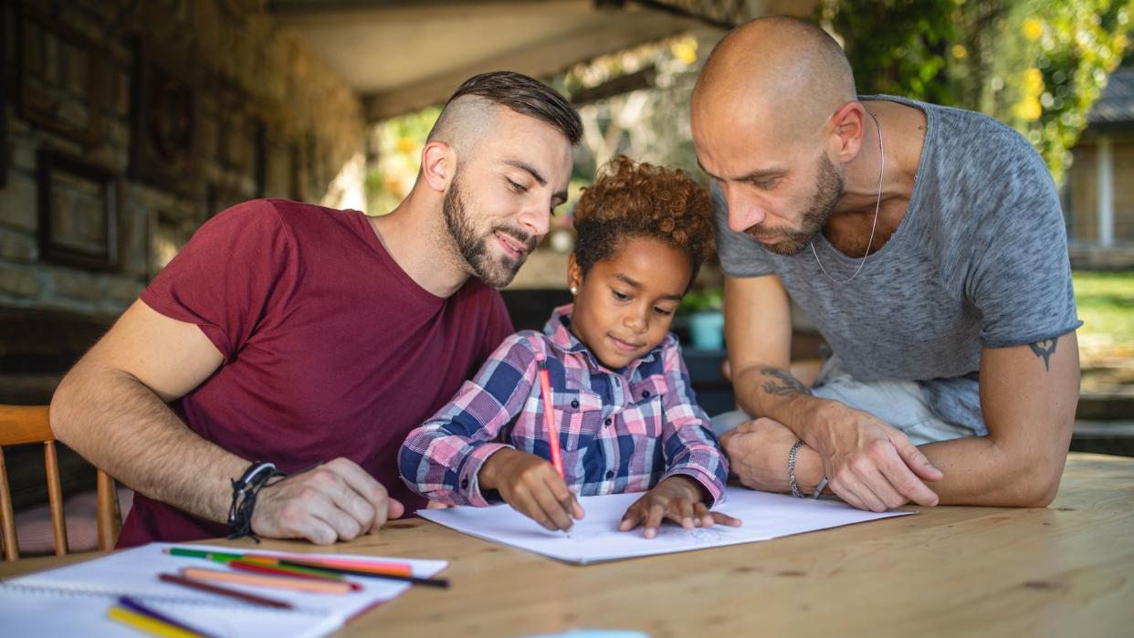 Beautiful and lovely gay homosexual couple enjoying their time spent together as a family with their beautiful adopted mixed race daughter.