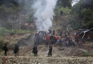 Gold miners try to put out a fire on machinery set by National Police, bottom, as soldiers stand guard on the periphery at an illegal mining operation, as part of the Armed Forces' "Operation Guamuez III" in Magui Payan, Colombia, Tuesday, April 20, 2021. None of the workers were detained during the destruction of machinery, but in previous days some machinists and material suppliers were detained, according to Army Col. Pedro Pablo Astaiza. (AP Photo/Fernando Vergara)
