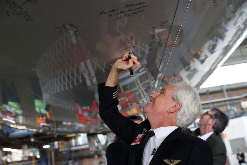 Un piloto de Qantas escribe un mensaje en la parte inferior de un jumbo Qantas 747 en el aeropuerto de Sídney, Australia, el 22 de julio de 2020
