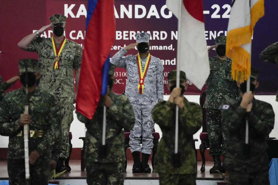 Philippine Navy Rear Adm. Caesar Bernard Valencia, center, acting Flag Officer In Command, salutes beside U.S. Navy Rear Adm. Derek Trinque, left, Commander of Expeditionary Strike Group 7 and Commander of Amphibious Force, 7th Fleet, during opening ceremonies of an annual joint military exercise called Kamandag the Tagalog acronym for "Cooperation of the Warriors of the Sea" at Fort Bonifacio, Taguig city, Philippines on Monday Oct. 3, 2022. More than 2,500 U.S. and Philippine marines launched combat exercises Monday to be able to jointly respond to any sudden crisis in a region long on tenterhooks over the South China Sea territorial disputes and China's increasingly hostile actions against Taiwan. (AP Photo/Aaron Favila)