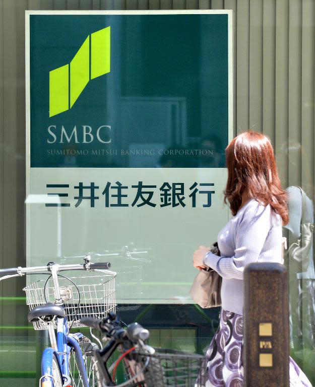 A woman walks in front of a signboard for Japan's Sumitomo Mitsui Banking Corp (SMBC) in Tokyo on May 15, 2013