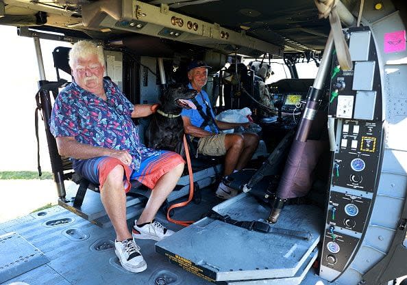 Tom O'Sullivan along with his dog, Jack, and Harry Marquard prepare to be evacuated in a Florida Army National Guard helicopter on October 2, 2022, in Pine Island, Florida. Residents of the island are being encouraged to leave because the only road onto the island is impassable and electricity and water remain knocked out after Hurricane Ian passed through the area.