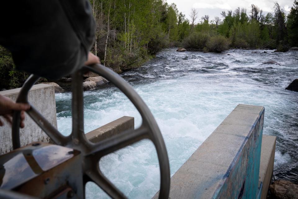 Brandon Overdorff, Highland Irrigation District watermaster, opens a gate at Fremont Lake Dam in Pinedale, Wyoming, on June 13, 2022. Spring runoff was at its peak and water was topping the dam. The lake supplies both the town and area farmers, but those supplies face an uncertain future because of downstream rights to lake water.