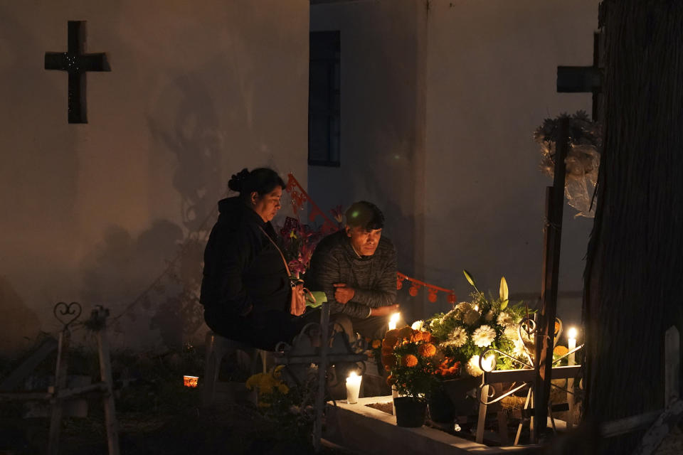 Personas sentadas junto a una tumba en el cementerio de San Gregorio Atlapulco durante las festividades del Día de Muertos en las afueras de la Ciudad de México, el miércoles 1 de noviembre de 2023. (AP Foto/Marco Ugarte)