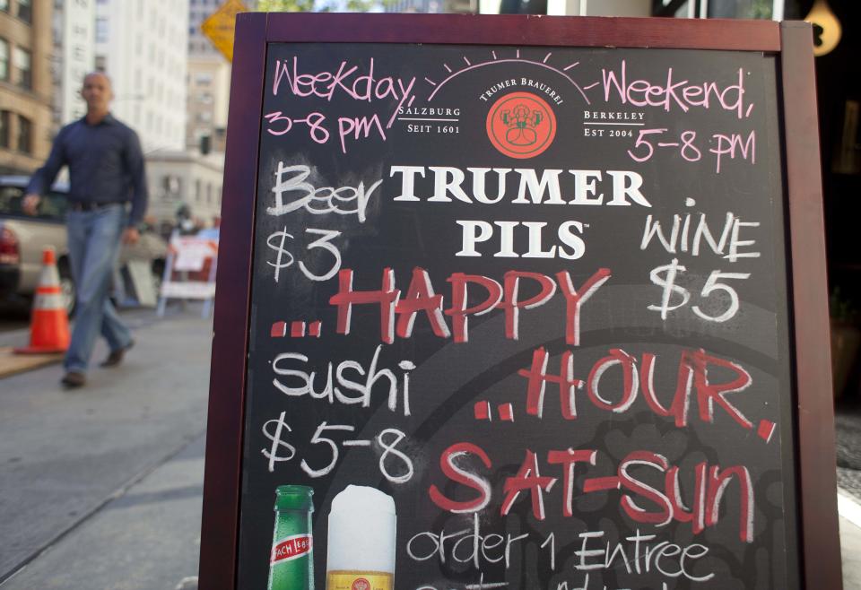 In this photo taken Monday, Aug. 6, 2012, a man walks past a sign advertising a happy hour at a restaurant on Second Street in San Francisco. The concept of happy hour when bars offer lower prices or two-for-one specials seems like a widespread tradition, but is actually illegal or restricted in quite a few places. (AP Photo/Eric Risberg)