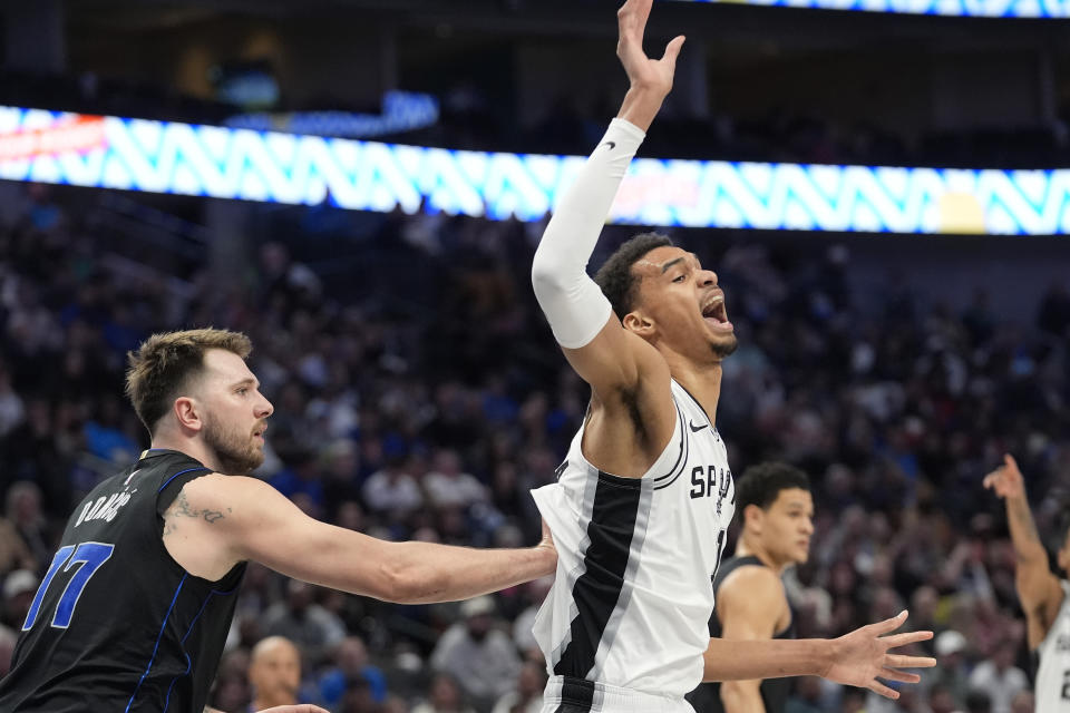 San Antonio Spurs center Victor Wembanyama (1) gets pushed by guard Luka Doncic (77) during the first half of an NBA basketball game in Dallas, Wednesday, Feb. 14, 2024. (AP Photo/LM Otero)