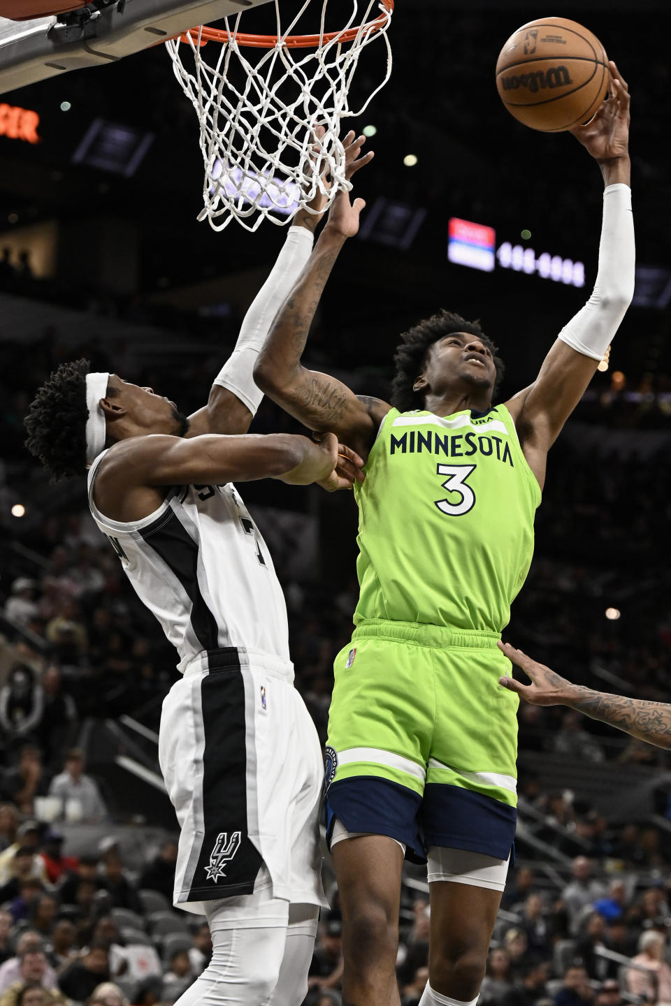 Minnesota Timberwolves' Jaden McDaniels (3) attempts to shoot against San Antonio Spurs' Josh Richardson during the first half of an NBA basketball game on Monday, March 14, 2022, in San Antonio. (AP Photo/Darren Abate)