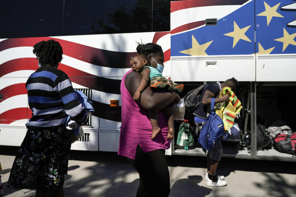 A young migrant sleeps on the shoulders of a woman as they prepare to board a bus toward Houston provided by a humanitarian organization after the migrants were released from U.S. Customs and Border Protection custody, Thursday, Sept. 23, 2021, in Del Rio, Texas. (AP Photo/Julio Cortez)
