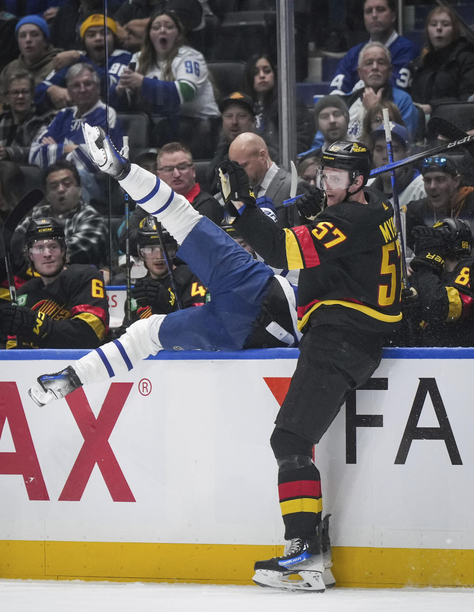 Vancouver Canucks' Tyler Myers, right, checks Toronto Maple Leafs' Calle Jarnkrok, left, into the Canucks' bench during the first period of an NHL hockey game in Vancouver, British Columbia, Saturday, Jan. 20, 2024. (Darryl Dyck/The Canadian Press via AP)