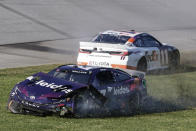 NASCAR Cup Series driver's Bubba Wallace (23) and Denny Hamlin (11) spin into the grass after a collision on the track during a NASCAR Cup Series auto race at Talladega Superspeedway, Sunday, April 21, 2024, in Talladega. Ala. (AP Photo/Russell Norris)