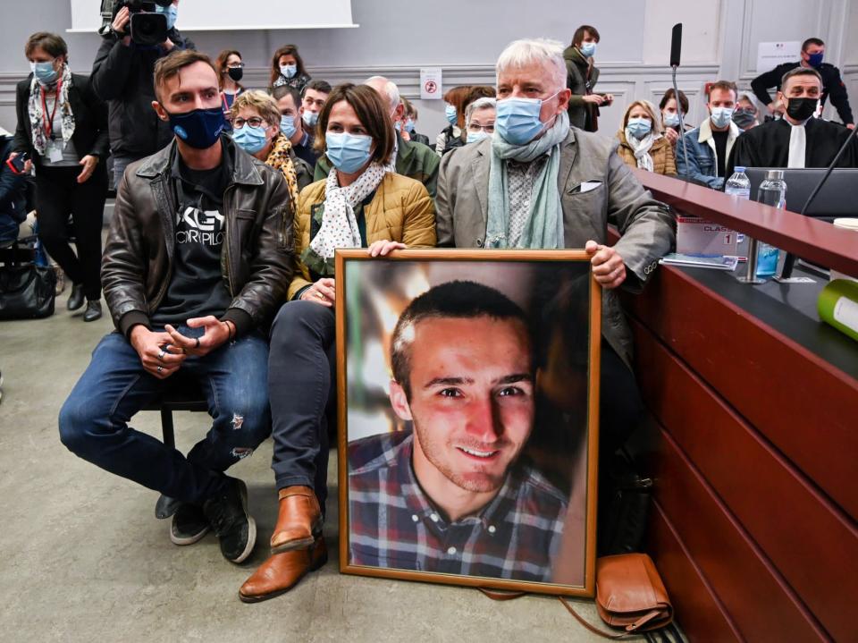 Les parents d'Arthur Noyer avec un portrait de leur fils mort, au procès de Nordahl Lelandais, le 3 mai 2021 - PHILIPPE DESMAZES / AFP