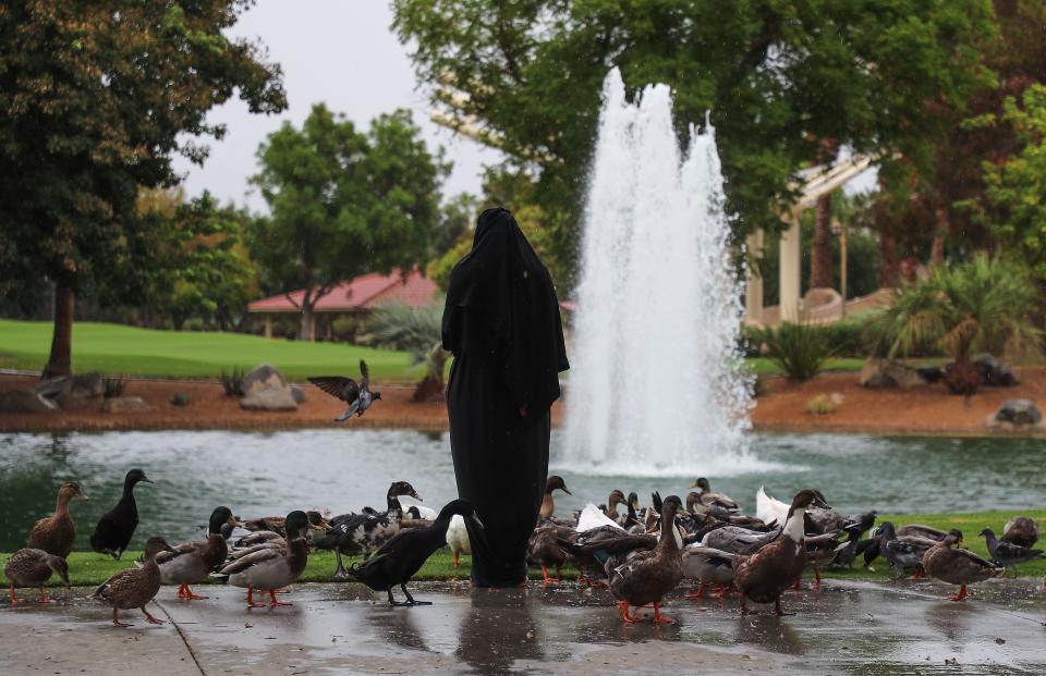 A woman feeds the ducks during a rainy day at the Palm Desert Civic Center Park in Palm Desert, Calif., Sept. 9, 2022.