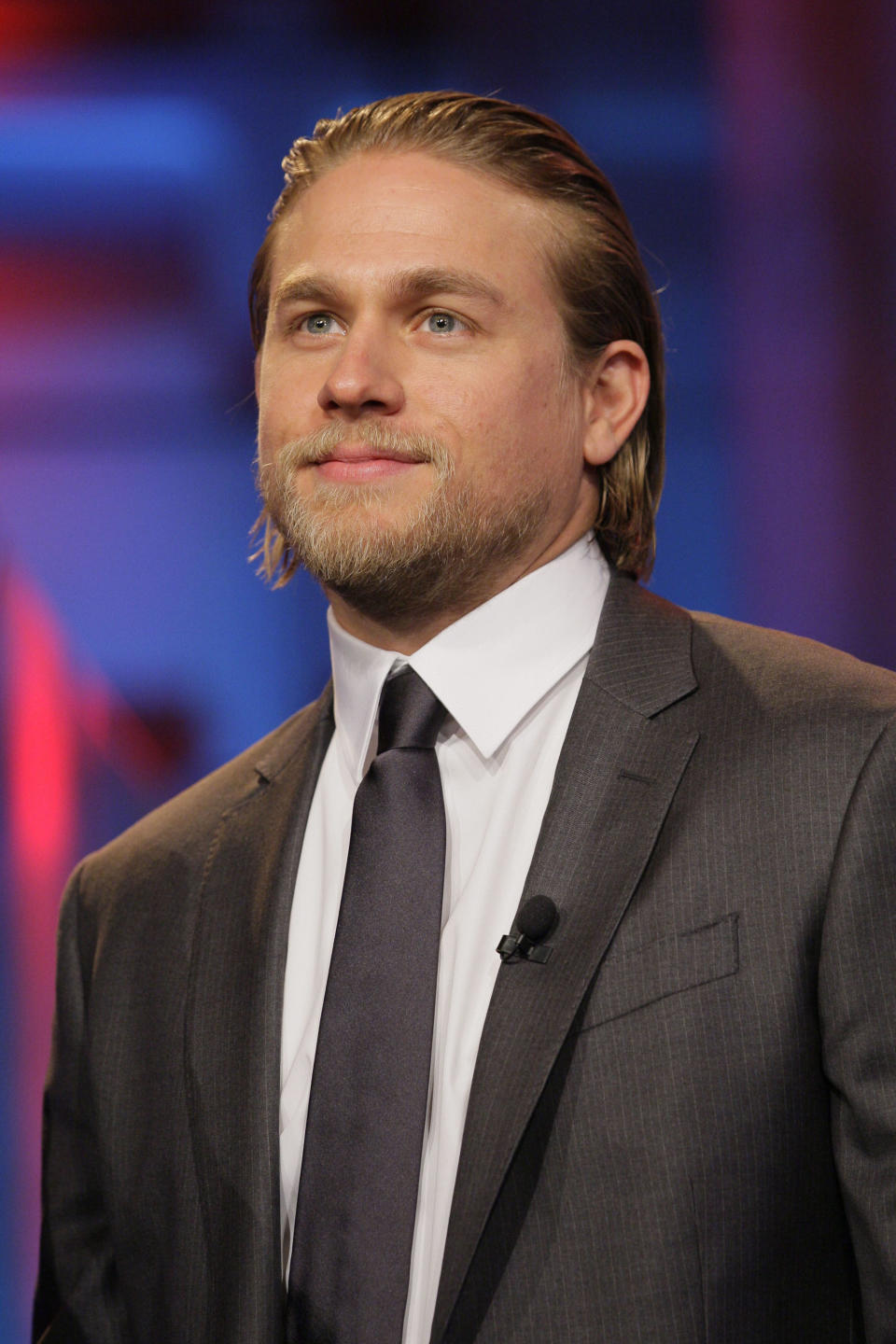 Charlie Hunnam wearing a suit and tie, looking off-camera at a formal event