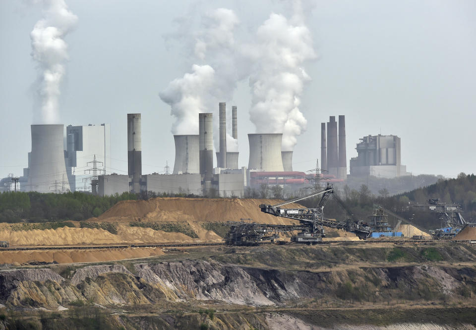 FILE - In this April 3, 2014 file photo giant machines dig for brown coal at the open-cast mining Garzweiler in front of a smoking power plant near the city of Grevenbroich in western Germany. World leaders breathed an audible sigh of relief that the United States under President Joe Biden is rejoining the global effort to curb climate change, a cause that his predecessor had shunned. (AP Photo/Martin Meissner, File)