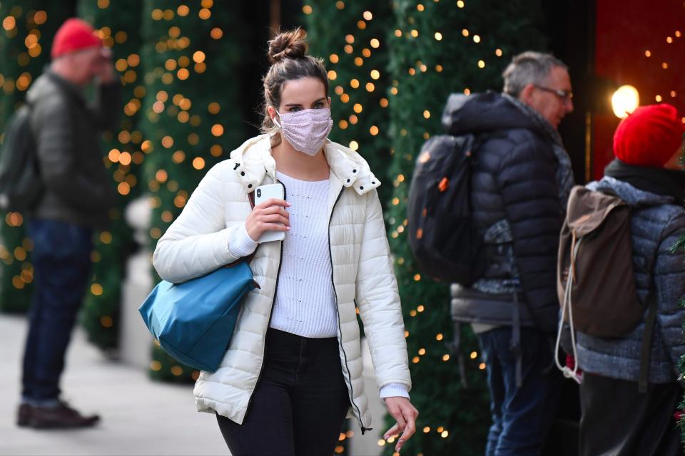 A pedestrian wearing a mask walks past shops and Christmas decorations in London’s Oxford Street (AFP via Getty Images)