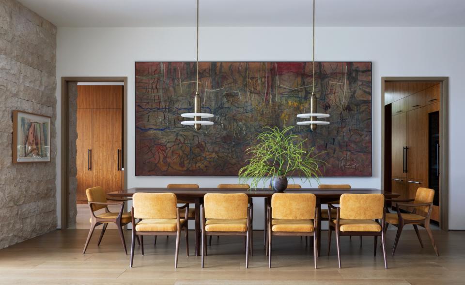 In the dining room, Gio Ponti chairs surround the custom Asher Israelow table. Pendants by Apparatus Studio and a large painting by Carlos Salas complement the sophisticated atmosphere.