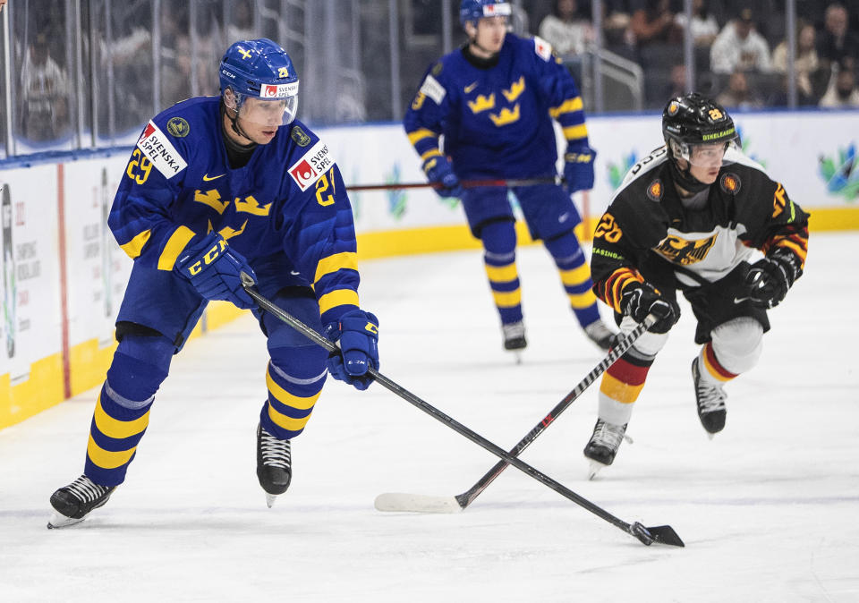 Sweden's Daniel Torgersson (29) is chased by Germany's Markus Schweiger during the first period of an IIHF world junior hockey championships game Monday, Aug. 15, 2022, in Edmonton, Alberta. (Jason Franson/The Canadian Press via AP)