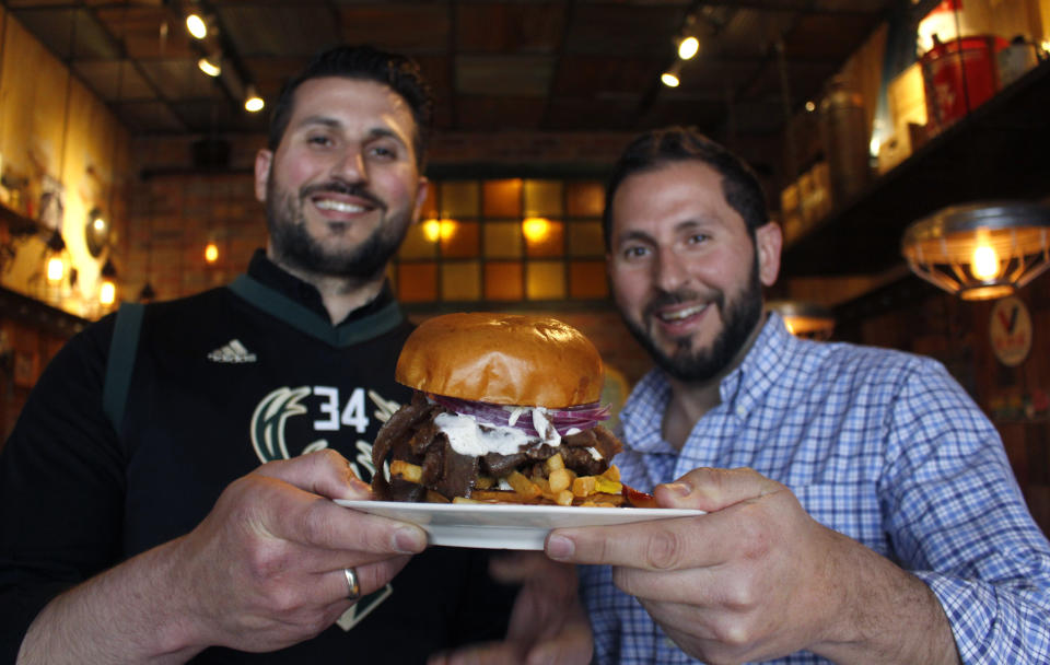 In this May 8, 2019 photo, Lou Liapis, left, and brother Pete Liapis hold the "Gyro Step" at their restaurant Georgie Porgie's in Oak Creek, Wis. They created the Greek-inspired sandwich, which includes a burger patty, gyro meat, feta cheese and tzatziki sauce, in honor of the fancy footwork of Bucks star Giannis Antetokuonmpo, who was born in Greece. It will be available during the playoffs. (AP Photo/Carrie Antlfinger)