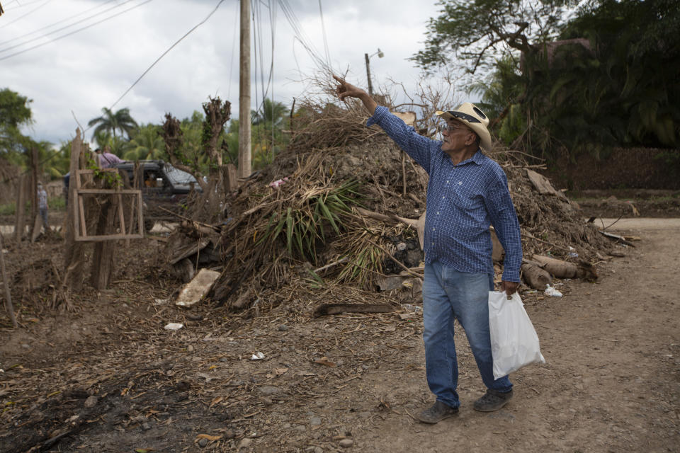 Juan Antonio Ramirez, 73, points to a tree that was hit by the floods during last year's hurricanes Eta and Iota in the San Jose neighborhood of La Lima, on the outskirts of San Pedro Sula, Honduras, where banana and sugar cane workers live, Monday, Jan. 11, 2021. Ramirez's children and grandchildren were among some 30 people who spent six days stranded on a corrugated metal roof surrounded by floodwaters in November. (AP Photo/Moises Castillo)