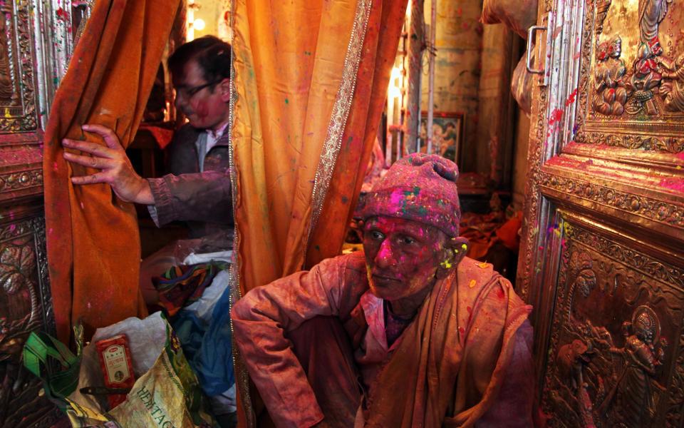 A Hindu priest, face covered with colored powder, waits for devotees at a temple on Holi, the festival of colors, in New Delhi, India, Monday, March 17, 2014. (AP Photo/Tsering Topgyal)