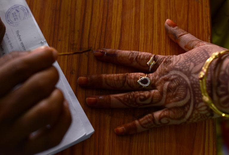 An Indian election official marks the finger of a voter with ink before she casts her ballot at a local polling station in the village of Sambhar in the Indian state of Rajasthan, on April 17, 2014