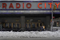 A man shovels snow from the entrance of Radio City Music Hall following a winter storm in Manhattan, New York, Tuesday, Feb. 2, 2021. (AP Photo/Seth Wenig)