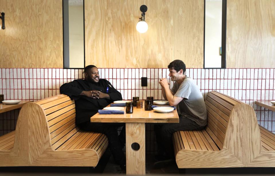 Chefs Keith Corbin and Daniel Patterson sit, laughing, in the wooden booths of their restaurant Alta Adams