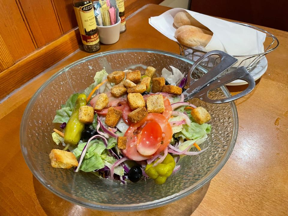 House salad with breadsticks in background at Olive Garden