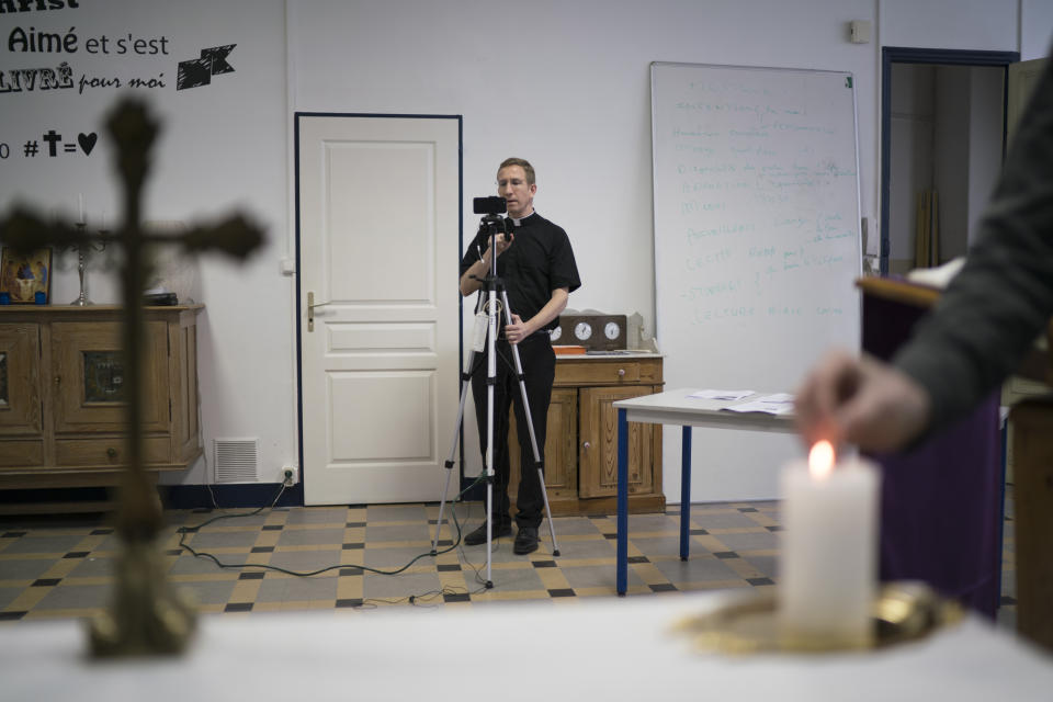 Priest Philippe Rochas of the St. Vincent de Paul church prepares a livestream of Sunday mass in Marseille, southern France, Sunday, March 22, 2020. As mass gatherings are forbidden due to measures to prevent the spread of COVID- 19, priests are using technology to reach worshippers forced to stay at home. For most people, the new coronavirus causes only mild or moderate symptoms. (AP Photo/Daniel Cole)