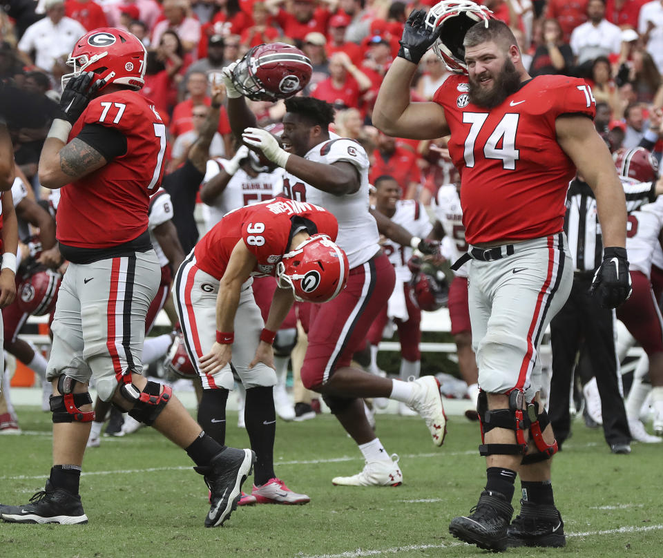 Georgia kicker Rodrigo Blankenship (98) bends over dejected reacting to missing a field goal attempt in double over time as South Carolina celebrates a 20-17 upset victory in an NCAA college football game, Saturday, Oct., 12, 2019, in Athens, Ga. (Curtis Compton/Atlanta Journal-Constitution via AP)