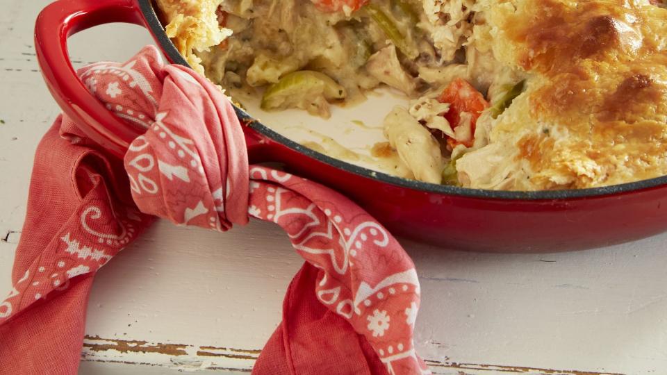 classic chicken pot pie in a red enamel cast iron pan with a scoop taken out