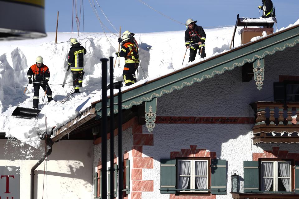 Firefighters clear the snow from a roof in Inzell, Germany, Wednesday, Jan. 16, 2019. (AP Photo/Matthias Schrader)