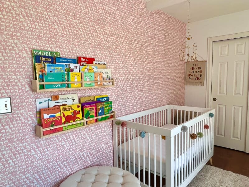 Pink and white wallpaper in book filled nursery.