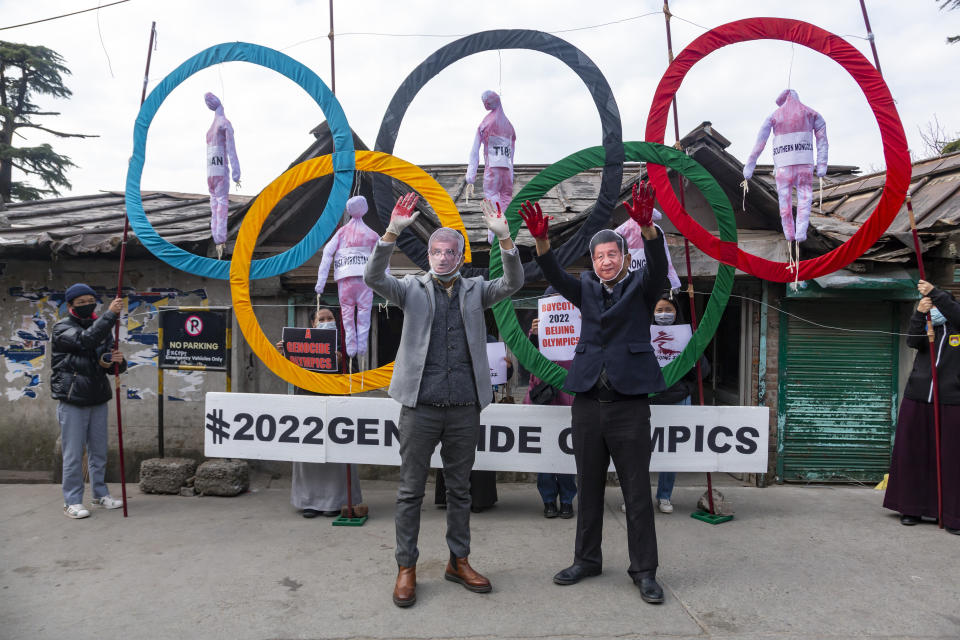 Activists wearing masks of the IOC President Thomas Bach and Chinese president Xi Jinping pose in front of the Olympic Rings during a street protest against the holding of 2022 Winter Olympics in Beijing in Dharmsala, India, Wednesday, Feb. 3, 2021. Five effigies represent Taiwan, Tibet, Hong Kong, Inner Mongolia and the region ethnic Uighurs call 'East Turkestan', under Chinese control. (AP Photo/Ashwini Bhatia)
