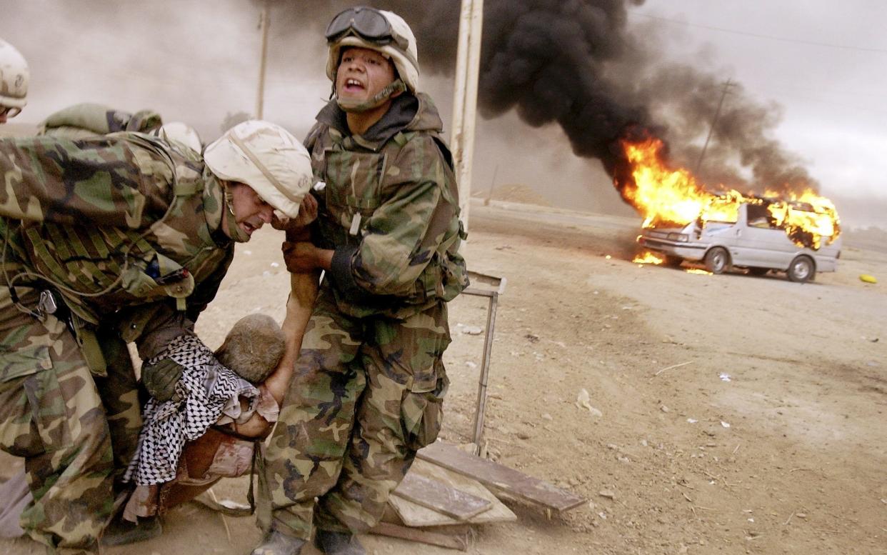 US soldiers drag a wounded civilian from a burning car in Iraq, April 2003 - Cheryl Diaz Meyer/AP