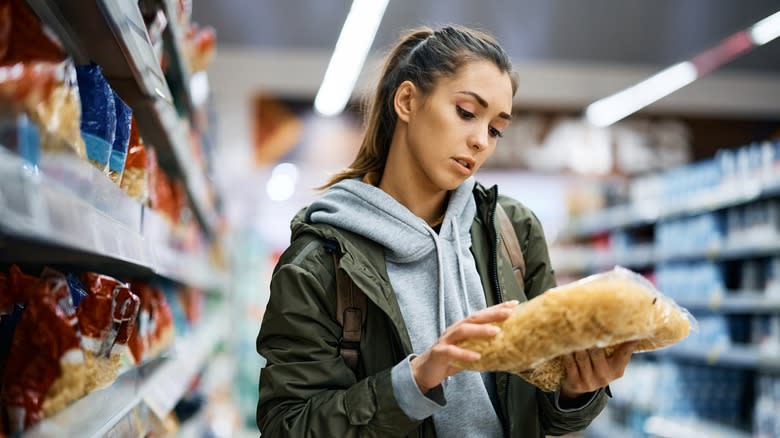 Woman reading the back of a bag of pasta